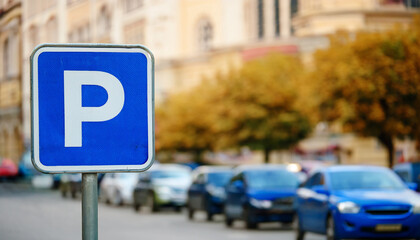 Blue city street parking sign, blurred cars in background. Urban car park space, traffic concept