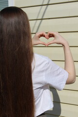 Fototapeta premium young girl with long beautiful hair against the background of a house