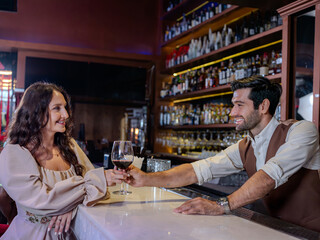 Bartender giving glass of wine to woman customer at bar counter .