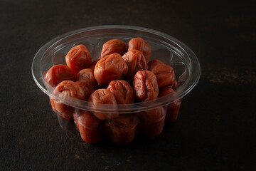 A view of a plastic container of umeboshi.
