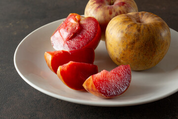 A view of a plate of dinosaur plums, featuring one plum that is sliced into wedges. © DAVID