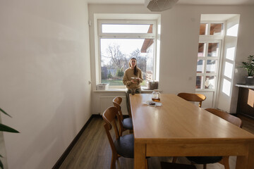 Woman drinking tea and eating a cake in her kitchen