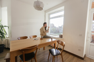 Woman drinking tea and eating a cake in her kitchen