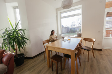 Woman drinking tea and eating a cake in her kitchen