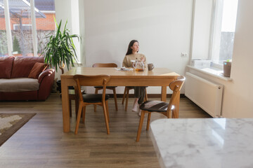 Woman drinking tea and eating a cake in her kitchen