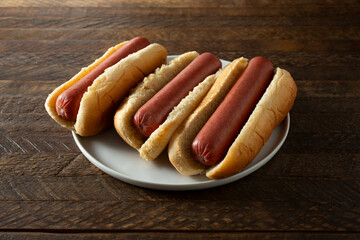 A view of a plate of three hot dogs.