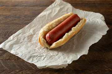 A closeup view of a hot dog on parchment paper.