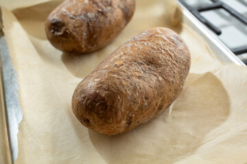 A view of two baked potatoes on a tray.