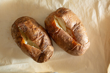 A top down view of two baked potatoes on a tray.