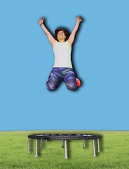Woman Joyfully Jumping Above a Mini Trampoline in Outdoor Setting with a Blue Sky Background