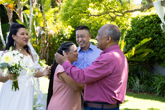 In garden, diverse seniors celebrating wedding, embracing and smiling joyfully