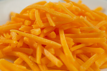 A closeup view of a pile of shredded cheddar cheese.