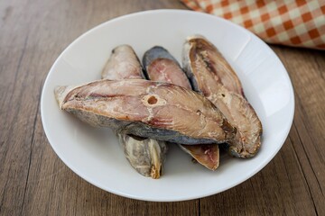 Salted King Fish in white plate on wooden background,indo pacific king mackerels, Spotted mackerel, dried fish