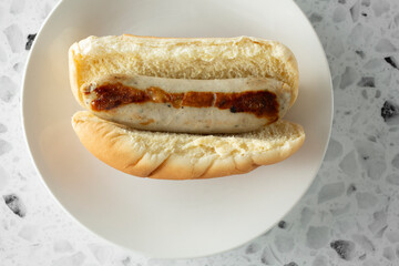 A top down view of a bratwurst hot dog, on a plate.