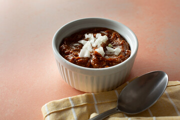 A view of a bowl of chili, topped with chopped onions.