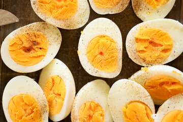 A closeup photo of boiled and halved chicken eggs sprinkled with salt and pepper, showcasing their texture and simplicity