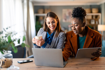 Professional Women Working Together on Laptops and Tablets in a Cozy Home Office Setting