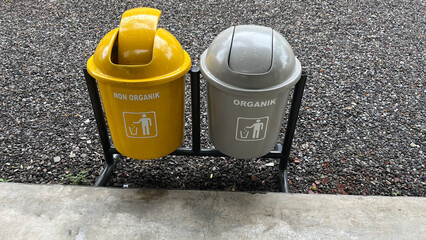 Two coloured recyclable bins in public area. Yellow and grey trash bins for organic and non-organic...