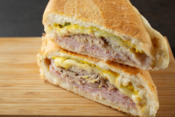 A closeup view of a Cuban sandwich stack, on a wood board.