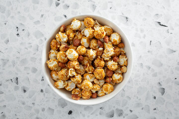 A top down view of a bowl of caramel coated popcorn snack.