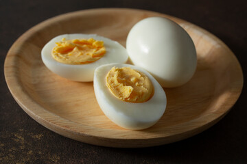 A view of some hard boiled eggs, on a plate, featuring one that is halved.