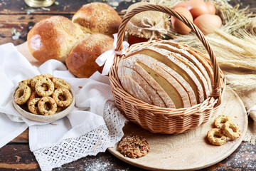 A large loaf of bread sliced for sandwiches inside the wicker basket. Surrounded by rolls and cookies.