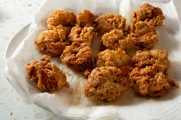A view of a layer of deep fried shrimp, drying on a paper towel.