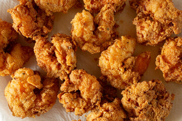 A top down view of a layer of deep fried shrimp, drying on a paper towel.