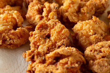 A closeup view of a layer of deep fried shrimp, drying on a paper towel.