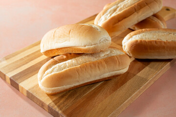 A view of a pile of French rolls, on a wood board.