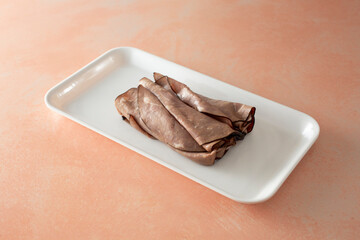 A view of a pile of roast beef slices, on a tray.