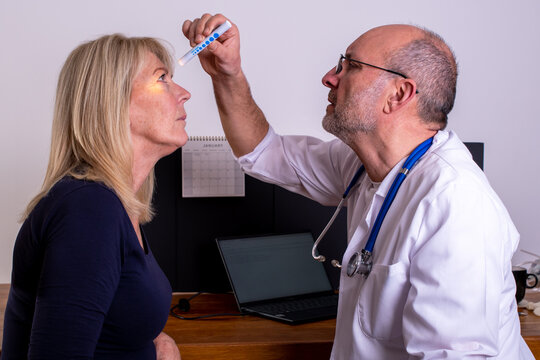 Eye examination. Doctor checking eyes for reaction to light, dilation of the pupil during a FAST test. Light sensitivity, Laser eye surgery. 