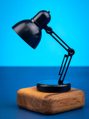 Close up of small black table lamp on blue background
