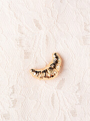 Close up of  golden  croissant brooch on white background