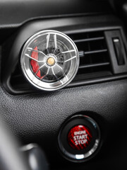 Close up of cast disc shaped air freshener on car dashboard vent