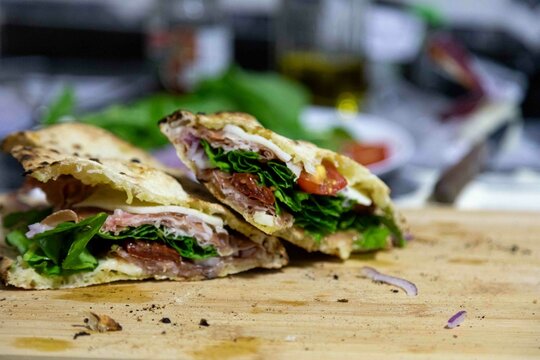 Traditional Italian Neapolitan panuozzo prepared with artisanal pizza dough, arugula and sun-dried tomatoes