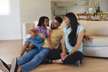 Happy family sitting on living room floor, enjoying quality time together