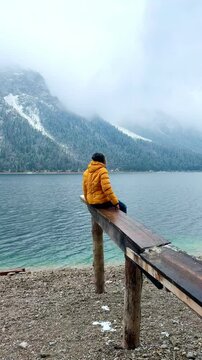sitting on the wooden pier over the alp lake, winter season on lake Plansee Austria