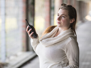 Woman with sunglasses using a walkie talkie in a car parking