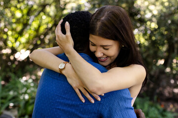 Diverse couple embracing warmly in garden, celebrating joyful moment together outdoors