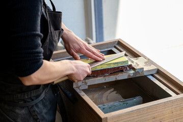 Un artisan professionnel nettoyant et affûtant des couteaux japonais, illustrant son expertise dans le métier de coutellerie traditionnelle.