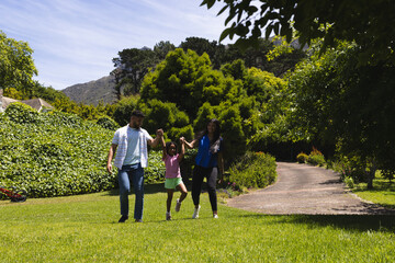 Fototapeta premium Family walking together in park, holding hands and enjoying sunny day outdoors