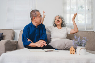 Obraz premium Happy elderly couple discussing pension savings while relaxing on cozy sofa in bright living room.