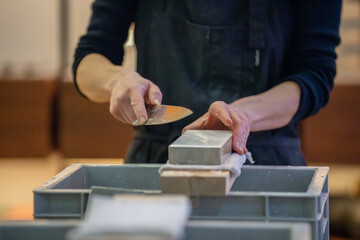 Un artisan professionnel nettoyant et affûtant des couteaux japonais, illustrant son expertise dans le métier de coutellerie traditionnelle.