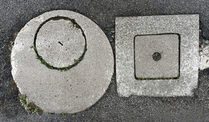 White and gray concrete sewer hatch on the asphalt road in the city
