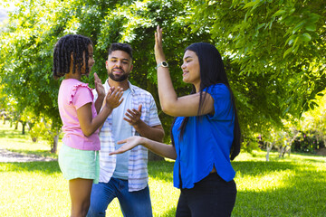 Family enjoying playful clapping game outdoors in sunny park setting