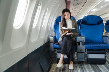 Woman Reading on Airplane: A composed woman engrossed in a book, seated comfortably on an airplane,...