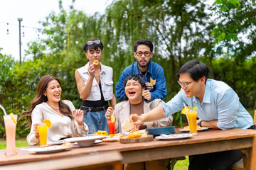Group of Happy Asian millennial generation people friends enjoy and fun celebration reunion meeting at outdoor dinner party with food and drink together in the garden at restaurant on holiday vacation