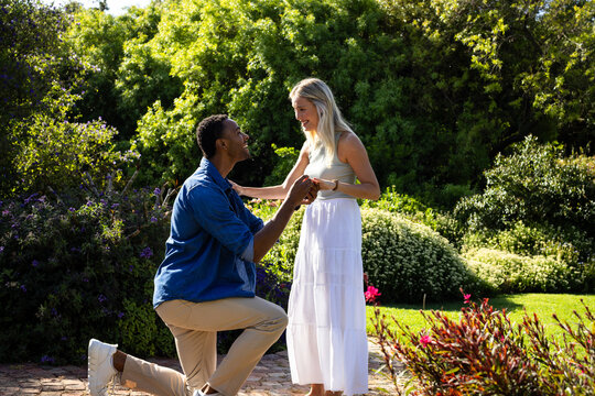 Man proposing to woman in beautiful garden, both smiling and joyful