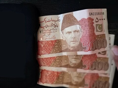 five thousand PKR rupees with chargeable power bank isolated on a wooden background.